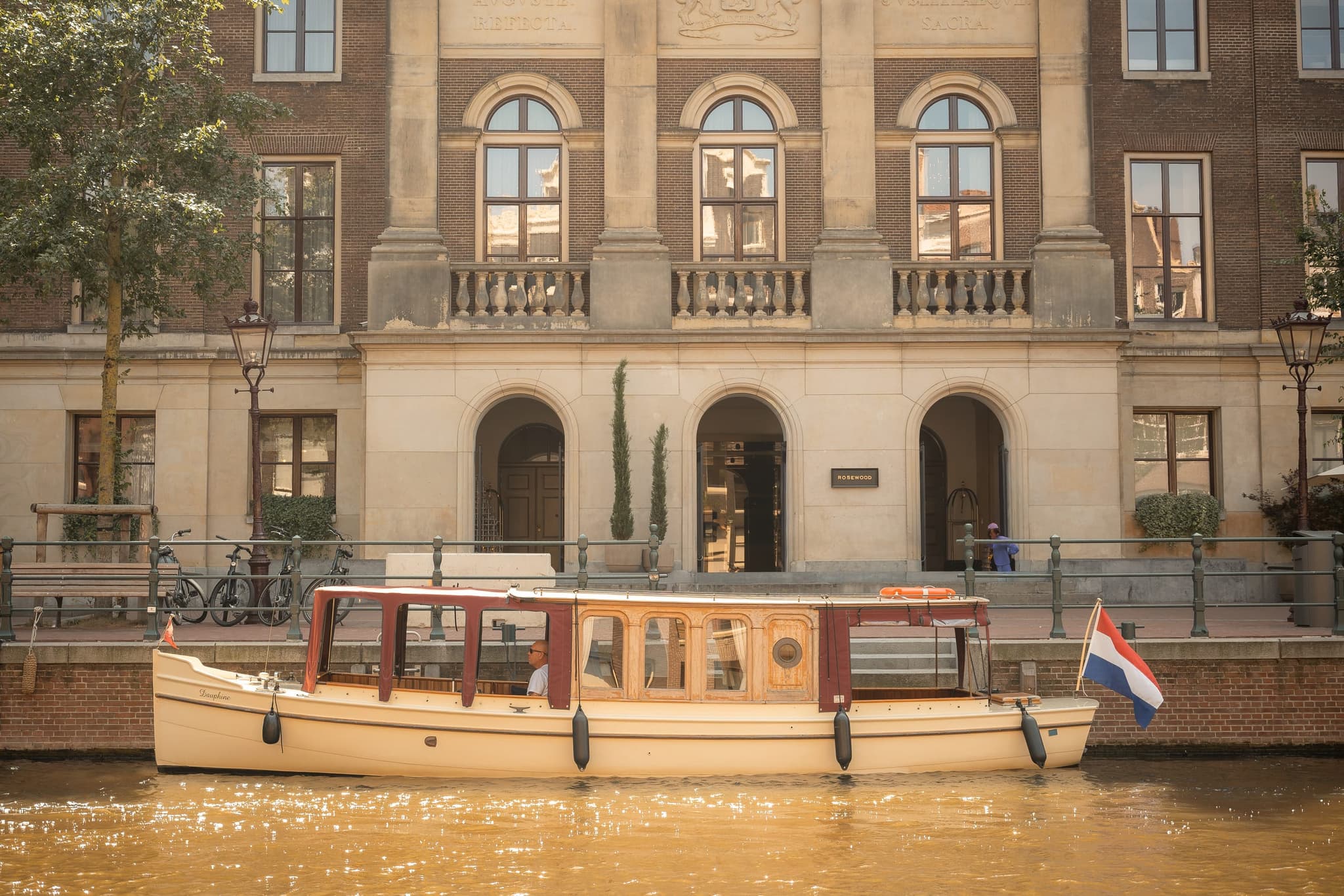 The Dauphine, a classic 1910 saloon boat, moored along an Amsterdam canal