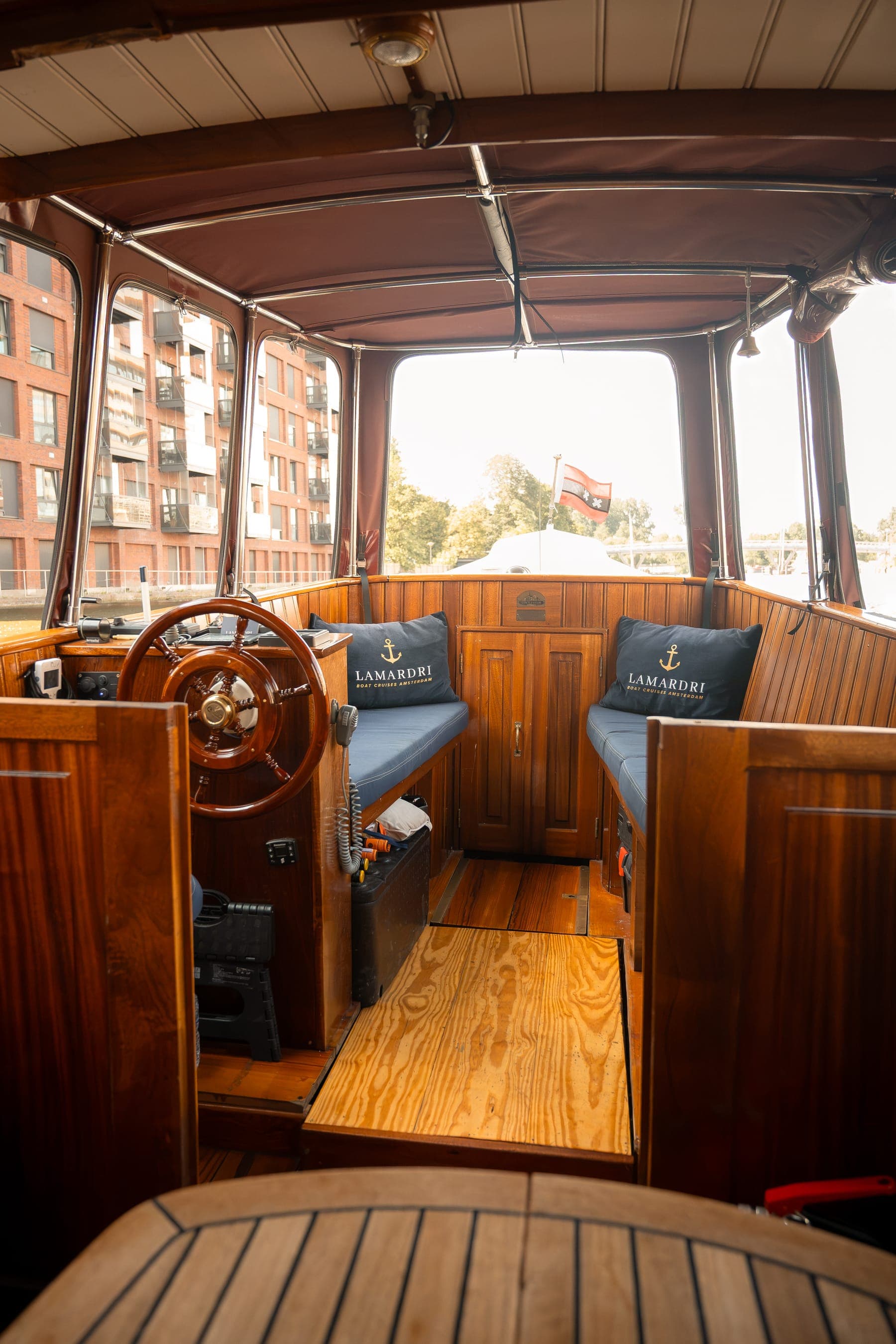 The wheelhouse of the Dauphine with a wooden helm and varnished woodwork