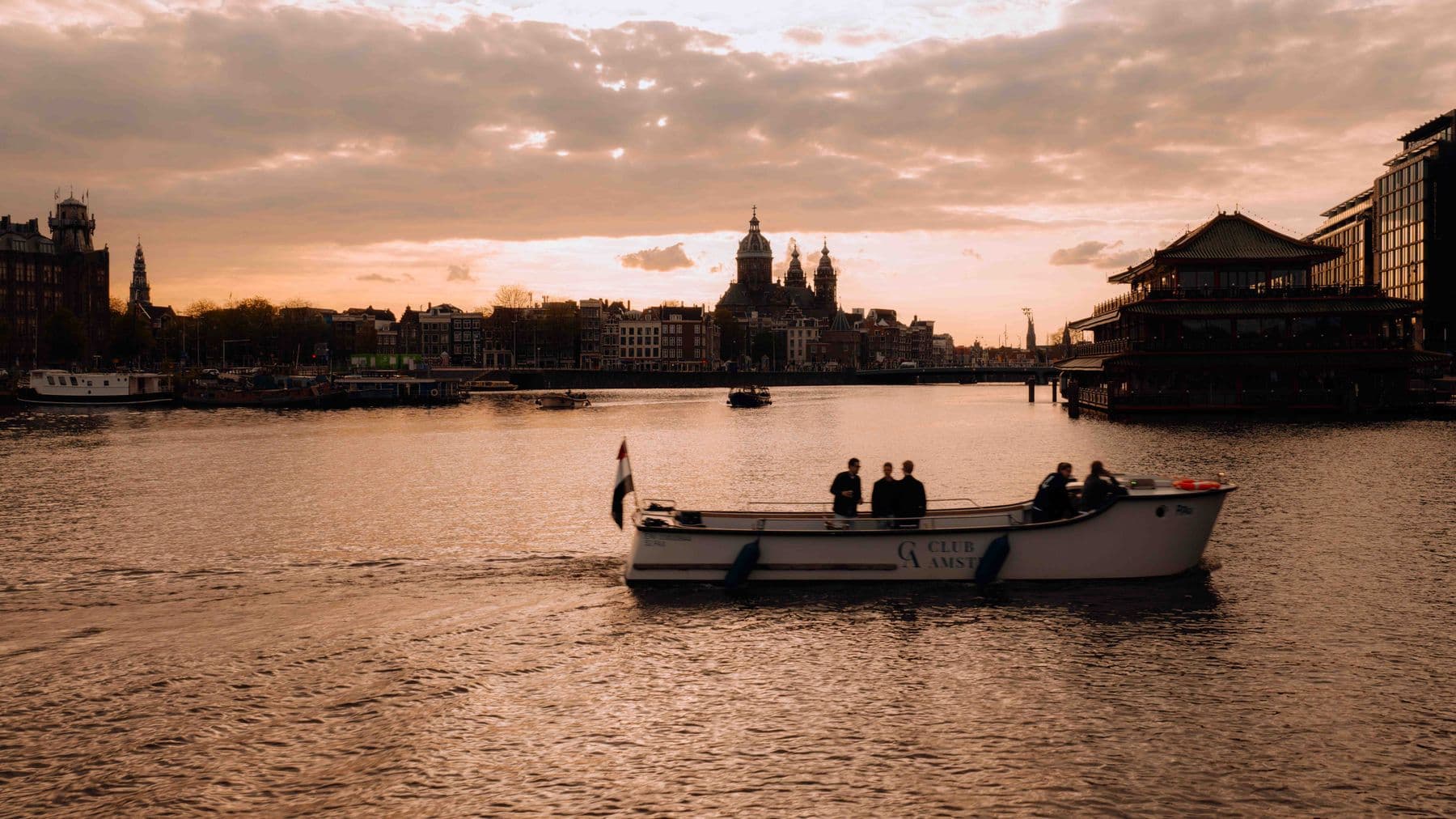Boot bij zonsondergang met Amsterdamse skyline